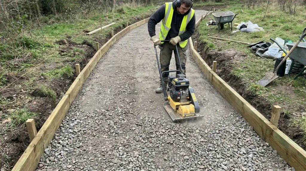 Compacting the sub-base for a garden path. 